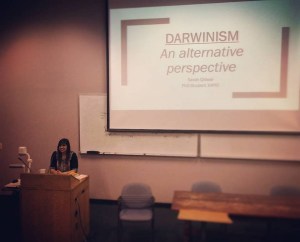 Sarah in front of a lectern and projector giving a presentation.